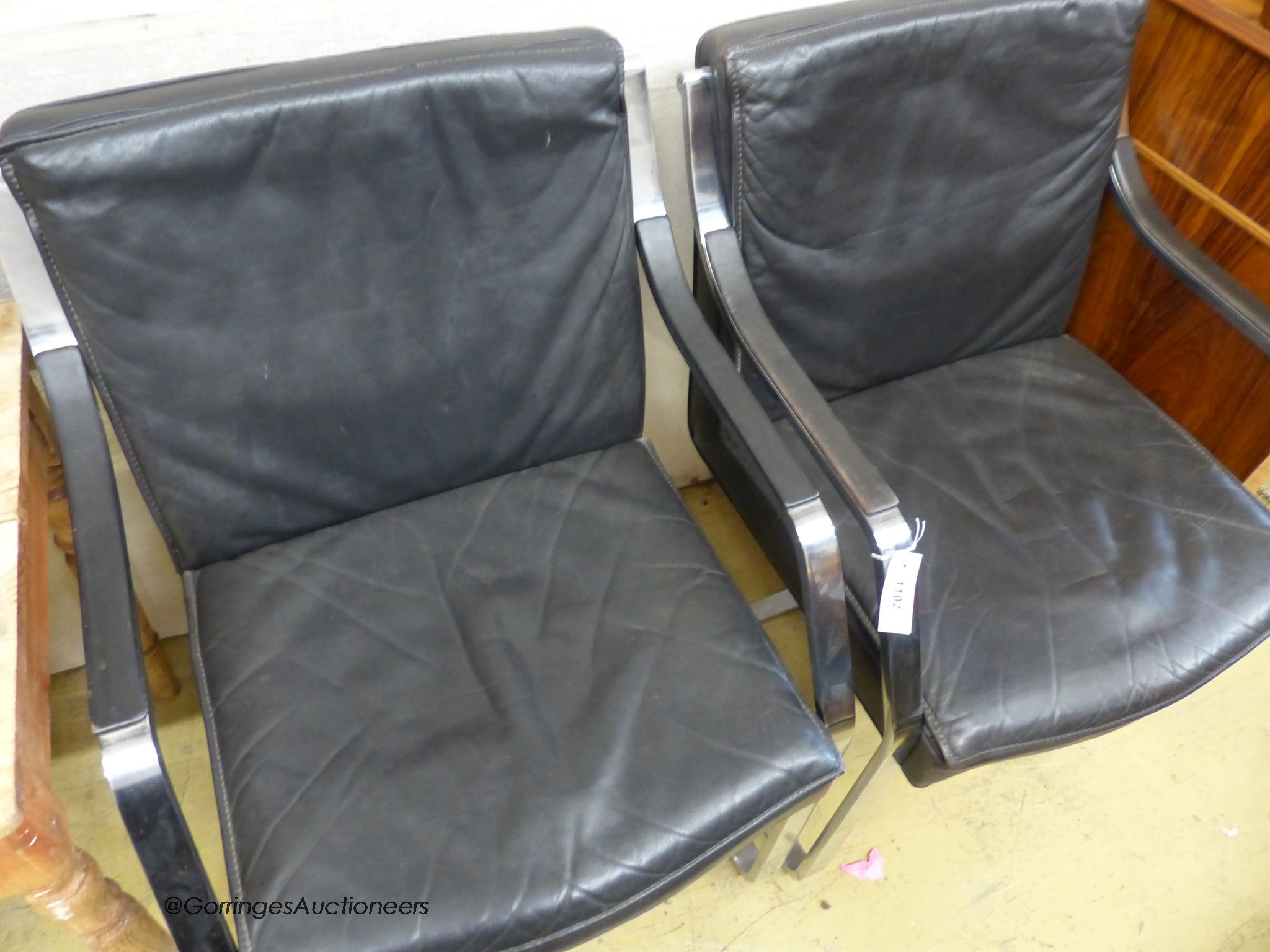 In the style of Knoll International. A pair of Mies Van deRohe design black leather and chrome cantilever chairs.
